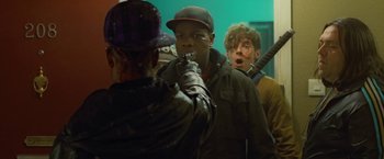 Movie still from “Attack the Block” (2011), directed by Joe Cornish – A group of men standing next to each other in a room; Medium shot, Over the shoulder angle