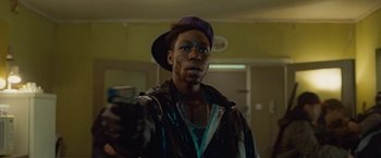 Movie still from “Attack the Block” (2011), directed by Joe Cornish – A man in a purple hat holding a gun; Close Up shot, Over the shoulder angle