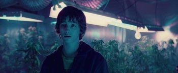 Movie still from “Attack the Block” (2011), directed by Joe Cornish – A young man standing next to a bunch of marijuana plants; Close Up shot, Over the shoulder angle