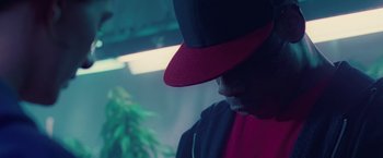 Movie still from “Attack the Block” (2011), directed by Joe Cornish – A man with a red hat is looking at a marijuana plant; Close Up shot, Low angle
