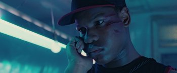 Movie still from “Attack the Block” (2011), directed by Joe Cornish – A man with a baseball cap on talking on a cell phone; Close Up shot, Low angle