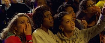 Movie still from “Attack the Block” (2011), directed by Joe Cornish – A group of people sitting next to each other on a stage; Close Up shot, High angle