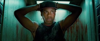 Movie still from “Attack the Block” (2011), directed by Joe Cornish – A young man in a black hat and a black shirt; Close Up shot, Low angle