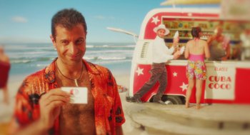 Movie still from “Attila Marcel” (2013), directed by Sylvain Chomet – A man holding a piece of paper standing next to a van on the beach; Medium shot, Over the shoulder angle