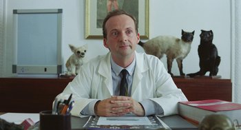 Movie still from “Attila Marcel” (2013), directed by Sylvain Chomet – A man sitting at a desk in front of a picture of a dog; Medium shot, Low angle