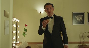 Movie still from “Attila Marcel” (2013), directed by Sylvain Chomet – A man in a tuxedo eating a piece of pizza; Medium shot, Over the shoulder angle