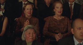 Movie still from “Attila Marcel” (2013), directed by Sylvain Chomet – Two older women are sitting in a row of people; Medium shot, Low angle