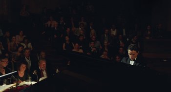 Movie still from “Attila Marcel” (2013), directed by Sylvain Chomet – A man sitting at a piano in front of an audience; Extreme Wide shot, High angle