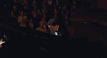 Movie still from “Attila Marcel” (2013), directed by Sylvain Chomet – A man sitting in front of an audience at a piano; Medium shot, Low angle