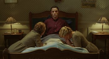 Movie still from “Attila Marcel” (2013), directed by Sylvain Chomet – A man sitting on a bed surrounded by two women; Medium shot, High angle