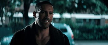 Movie still from “Avengement” (2019), directed by Jesse V. Johnson – A person wearing a black shirt; Close Up shot, Over the shoulder angle