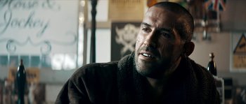 Movie still from “Avengement” (2019), directed by Jesse V. Johnson – A person sitting in a room; Close Up shot, Over the shoulder angle