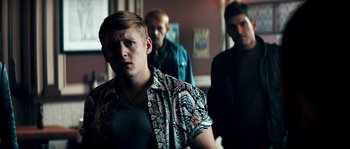 Movie still from “Avengement” (2019), directed by Jesse V. Johnson – A man in a patterned shirt standing in front of two other men; Medium shot, Over the shoulder angle