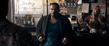 Movie still from “Avengement” (2019), directed by Jesse V. Johnson – A man with a beard is wearing a robe; Medium shot, Over the shoulder angle