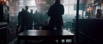Movie still from “Avengement” (2019), directed by Jesse V. Johnson – A group of people standing around a room; Wide shot, Low angle