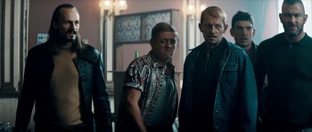 Movie still from “Avengement” (2019), directed by Jesse V. Johnson – A group of men standing next to each other in a room; Medium shot, Low angle