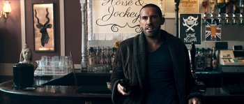 Movie still from “Avengement” (2019), directed by Jesse V. Johnson – A man holding a gun while standing in front of a bar; Close Up shot, Over the shoulder angle