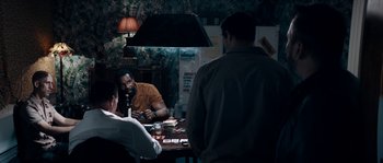Movie still from “Avengement” (2019), directed by Jesse V. Johnson – A group of people sitting around a table; Medium shot, Over the shoulder angle