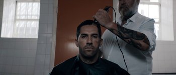 Movie still from “Avengement” (2019), directed by Jesse V. Johnson – A man getting his hair cut by a barber; Close Up shot, Over the shoulder angle