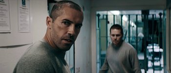 Movie still from “Avengement” (2019), directed by Jesse V. Johnson – Two men are standing in a room and one of them is looking at the camera; Close Up shot, Over the shoulder angle