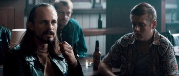 Movie still from “Avengement” (2019), directed by Jesse V. Johnson – A group of men sitting at a table drinking beer; Close Up shot, Over the shoulder angle