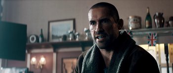 Movie still from “Avengement” (2019), directed by Jesse V. Johnson – A person with a towel around his neck; Close Up shot, Over the shoulder angle
