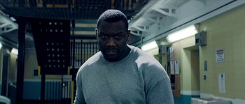 Movie still from “Avengement” (2019), directed by Jesse V. Johnson – A man in a gray sweatshirt is looking at the camera; Close Up shot, Low angle