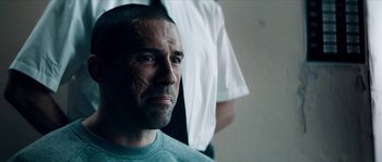 Movie still from “Avengement” (2019), directed by Jesse V. Johnson – A person wearing a shirt; Close Up shot, Over the shoulder angle