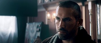 Movie still from “Avengement” (2019), directed by Jesse V. Johnson – Close up of a man's face in a living room setting; Close Up shot, Over the shoulder angle