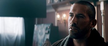 Movie still from “Avengement” (2019), directed by Jesse V. Johnson – A person sitting in a room; Close Up shot, Over the shoulder angle