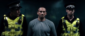 Movie still from “Avengement” (2019), directed by Jesse V. Johnson – A man in a gray shirt is looking at the camera; Close Up shot, Low angle