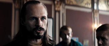 Movie still from “Avengement” (2019), directed by Jesse V. Johnson – A man with long hair and blue eyes stares at the camera; Close Up shot, Over the shoulder angle