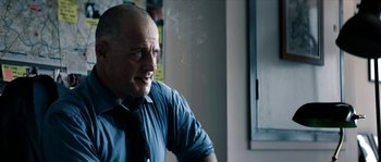 Movie still from “Avengement” (2019), directed by Jesse V. Johnson – A man in a blue shirt and a black neck tie; Close Up shot, Over the shoulder angle