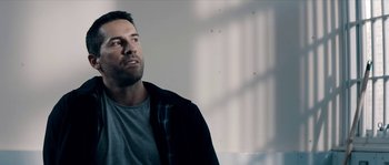 Movie still from “Avengement” (2019), directed by Jesse V. Johnson – A person wearing a shirt and jacket; Close Up shot, Over the shoulder angle