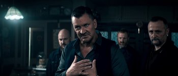 Movie still from “Avengement” (2019), directed by Jesse V. Johnson – A group of men standing next to each other in a room; Close Up shot, Over the shoulder angle