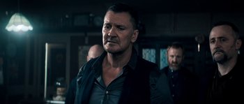 Movie still from “Avengement” (2019), directed by Jesse V. Johnson – A person wearing a black shirt; Close Up shot, Over the shoulder angle