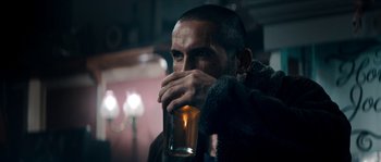 Movie still from “Avengement” (2019), directed by Jesse V. Johnson – A man drinking from a glass in a bar; Close Up shot, Over the shoulder angle