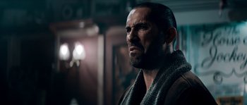 Movie still from “Avengement” (2019), directed by Jesse V. Johnson – A man with a beard is looking into the distance; Close Up shot, Low angle