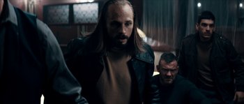 Movie still from “Avengement” (2019), directed by Jesse V. Johnson – A man with long hair is standing in front of another man; Medium shot, Over the shoulder angle