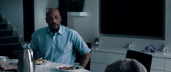 Movie still from “Avengement” (2019), directed by Jesse V. Johnson – A man sitting at a table with a plate of food in front of him; Medium shot, Over the shoulder angle