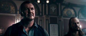 Movie still from “Avengement” (2019), directed by Jesse V. Johnson – An older man in a dark room looking at the camera; Close Up shot, Low angle