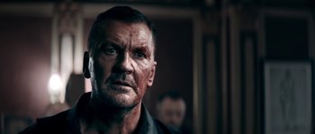 Movie still from “Avengement” (2019), directed by Jesse V. Johnson – A person wearing a black shirt; Close Up shot, Low angle