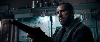 Movie still from “Avengement” (2019), directed by Jesse V. Johnson – A person holding a book in a room; Close Up shot, Over the shoulder angle