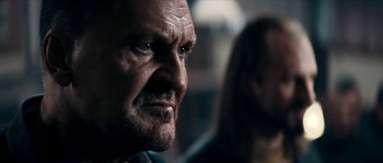 Movie still from “Avengement” (2019), directed by Jesse V. Johnson – An older man with a goatee stares into the camera; Close Up shot, Over the shoulder angle