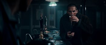 Movie still from “Avengement” (2019), directed by Jesse V. Johnson – A man sitting at a bar drinking a beverage; Medium shot, Low angle
