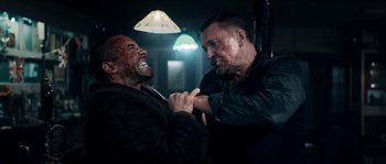 Movie still from “Avengement” (2019), directed by Jesse V. Johnson – Two men are fighting in a dark room; Medium shot, Over the shoulder angle