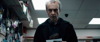 Movie still from “Avengement” (2019), directed by Jesse V. Johnson – An older man holding a piece of paper in his hand; Close Up shot, Low angle
