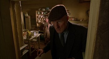 Movie still from “Babe” (1995), directed by Chris Noonan – An older man wearing a hat and a suit in a kitchen; Medium shot, Low angle