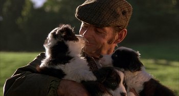 Movie still from “Babe” (1995), directed by Chris Noonan – A man holding two puppies in his arms; Close Up shot, Over the shoulder angle
