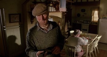 Movie still from “Babe” (1995), directed by Chris Noonan – An older man wearing a hat in a room; Medium shot, Low angle